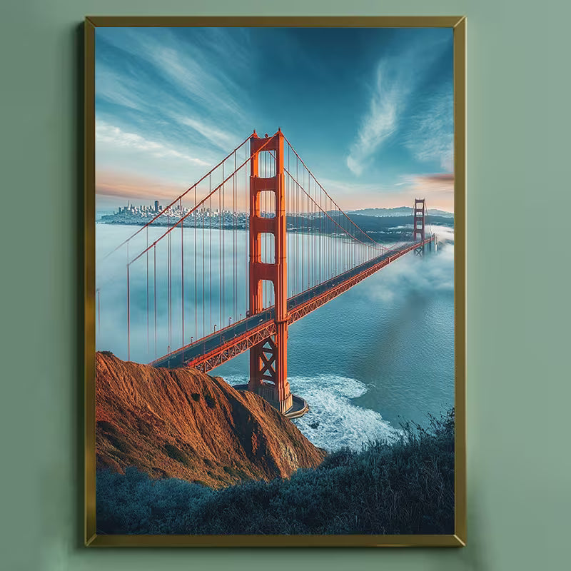 Диамантен гоблен с изглед към моста Голдън Гейт в Сан Франциско, заснет от висока гледна точка над морето, с червено-оранжеви метални конструкции, обгърнати от мъгла, спокойна синя вода отдолу, скалист бряг на преден план и меко осветено небе с облаци, създаващо усещане за простор, дълбочина и емблематичен градски пейзаж.