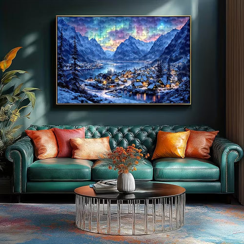 Пъзел с планински зимен пейзаж и малко селце край езеро, подреден и поставен в рамка над зелена канапе в уютен интериор.