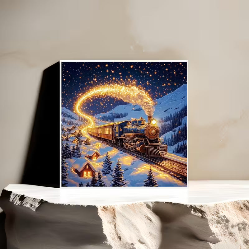 Декоративна картина с илюстрация на парен влак в заснежен планински пейзаж през нощта, със златиста светеща следа и уютни къщички сред снега.