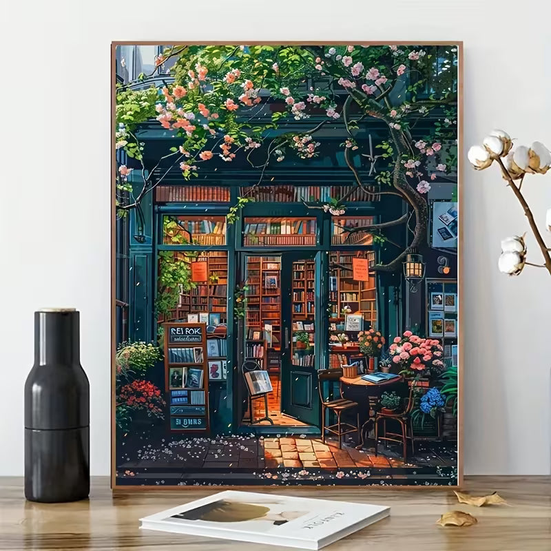 Декоративна картина в рамка с илюстрация на книжарница с отворена врата, рафтове с книги и цъфнали цветя, подходяща за уютен интериор и арт декорация.
